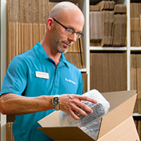 An associate at The UPS Store packing and shipping a returned item